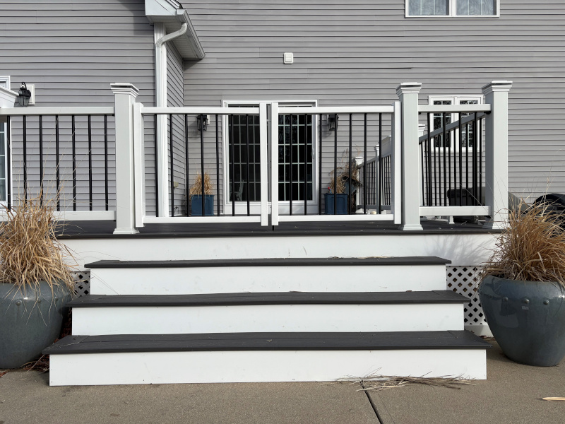 This Litchfield, NH project features a clean, modern custom deck fencing installation by Granite State Fence, designed for both safety and style. The focal point of the project is a 6-foot-high custom composite double drive gate with a 78-inch opening, combining white composite posts and rails with black vertical balusters. The contrast creates a sharp, timeless look that complements the deck while maintaining clear sightlines to the backyard and pool area. Each post was carefully set and capped for a finished appearance, and the double gate was custom-built to provide smooth operation and durability. This setup offers secure access while still feeling open and inviting, an ideal solution for decks overlooking pools or large outdoor living spaces. From precise spacing to clean hardware placement, every detail was thoughtfully executed to ensure long-term performance and a polished final result. A great example of how custom fencing can elevate both the function and aesthetics of an outdoor space.