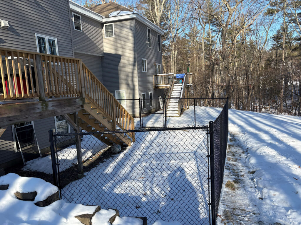 Granite State Fence installed this 6-foot black chain link fence in Salem, NH, creating a secure and defined backyard space for this property.