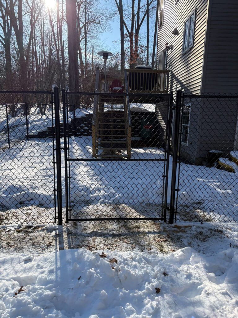 Granite State Fence installed this 6-foot black chain link fence in Salem, NH, creating a secure and defined backyard space for this property.